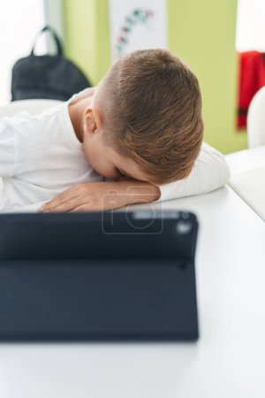 Photo for Adorable hispanic boy student tired leaning on the desk at classroom - Royalty Free Image
