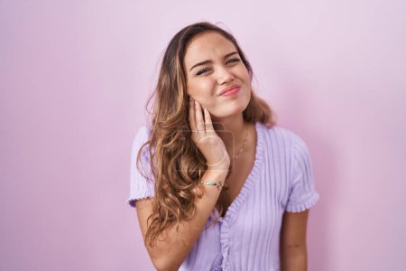 Téléchargez les photos : Young hispanic woman standing over pink background touching mouth with hand with painful expression because of toothache or dental illness on teeth. dentist - en image libre de droit