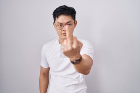 Photo for Young asian man standing over white background showing middle finger, impolite and rude fuck off expression - Royalty Free Image