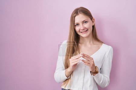 Téléchargez les photos : Jeune femme caucasienne debout sur fond rose mains ensemble et doigts croisés souriant détendu et joyeux. succès et optimisme - en image libre de droit