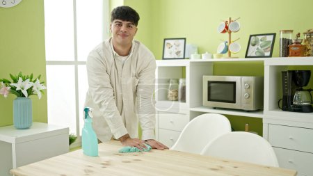 Photo for Young hispanic man smiling confident cleaning table at dinning room - Royalty Free Image