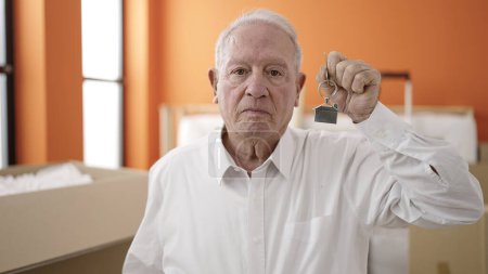 Photo for Senior holding keys of new home with sad face at new home - Royalty Free Image