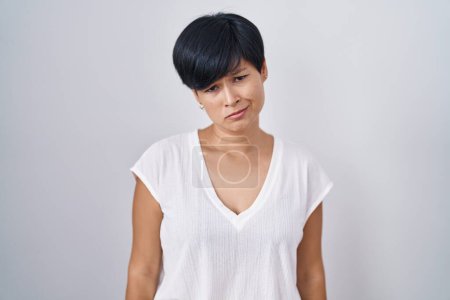 Foto de Mujer asiática joven con el pelo corto de pie sobre el fondo aislado deprimido y la preocupación por la angustia, llorando enojado y miedo. expresión triste. - Imagen libre de derechos