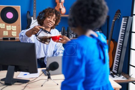 Téléchargez les photos : African american women musicians smiling confident drinking coffee at music studio - en image libre de droit