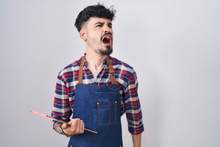 Téléchargez les photos : Young hispanic man with beard wearing waiter apron holding clipboard angry and mad screaming frustrated and furious, shouting with anger. rage and aggressive concept. - en image libre de droit