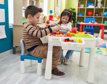 Téléchargez les photos : Adorable garçon et fille jouant avec des blocs de construction assis sur la table à la maternelle - en image libre de droit