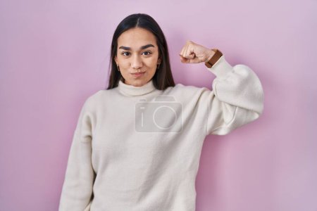 Foto de Joven sur asiático mujer de pie sobre rosa fondo fuerte persona mostrando brazo músculo, confiado y orgulloso de poder - Imagen libre de derechos