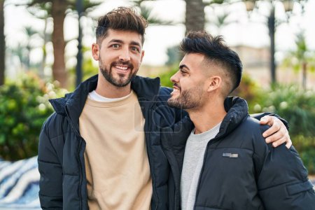 Téléchargez les photos : Jeune couple souriant confiant se serrant dans ses bras au parc - en image libre de droit