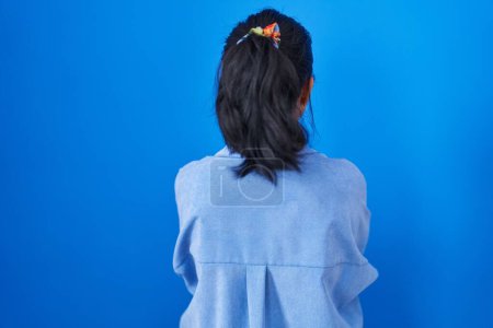 Photo for Asian young woman standing over blue background standing backwards looking away with crossed arms - Royalty Free Image