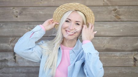 Téléchargez les photos : Jeune femme blonde touriste souriant confiant portant un chapeau d'été sur fond de bois isolé - en image libre de droit