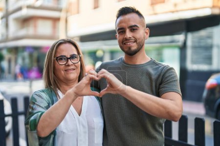 Photo for Man and woman mother and daugther doing heart gesture with hands at street - Royalty Free Image