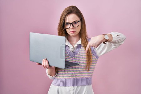 Photo for Young caucasian woman working using computer laptop pointing down looking sad and upset, indicating direction with fingers, unhappy and depressed. - Royalty Free Image