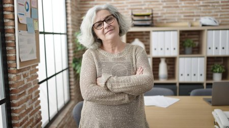 Photo for Middle age woman with grey hair business worker smiling confident standing with arms crossed gesture at office - Royalty Free Image