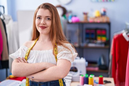 Photo for Young redhead woman tailor smiling confident standing with arms crossed gesture at clothing factory - Royalty Free Image