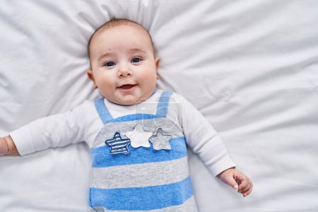 Photo for Adorable baby smiling confident lying on bed at bedroom - Royalty Free Image