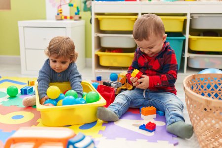 Photo for Adorable boys playing with balls and construction blocks sitting on floor at kindergarten - Royalty Free Image