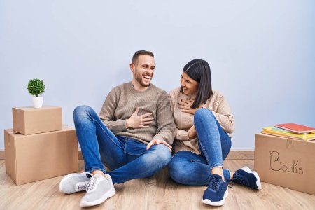 Photo for Young couple moving to a new home smiling and laughing hard out loud because funny crazy joke with hands on body. - Royalty Free Image