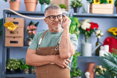 Téléchargez les photos : Middle age grey-haired man florist smiling confident standing with arms crossed gesture at flower shop - en image libre de droit