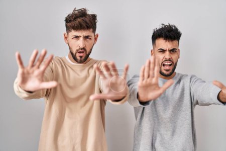 Photo for Young homosexual couple standing over white background doing stop gesture with hands palms, angry and frustration expression - Royalty Free Image