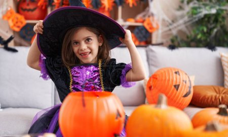 Foto de Adorable chica hispana vistiendo traje de bruja teniendo fiesta de Halloween en casa - Imagen libre de derechos