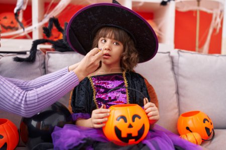 Photo for Adorable hispanic girl wearing witch costume having halloween makeup at home - Royalty Free Image