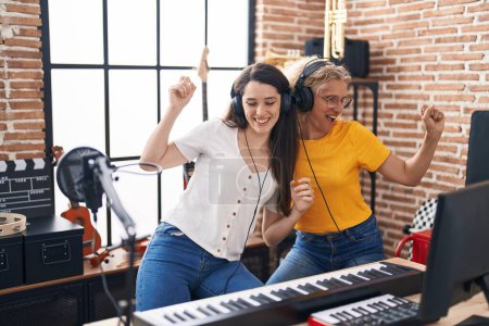 Two women musicians listening to music dancing at music studio