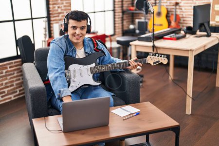 Téléchargez les photos : Young non binary man musician having online electric guitar lesson at music studio - en image libre de droit