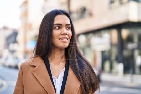 Téléchargez les photos : Jeune femme hispanique souriant confiant debout dans la rue - en image libre de droit
