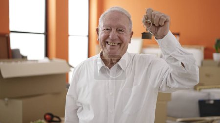 Téléchargez les photos : Senior souriant tenant les clés de la nouvelle maison à la nouvelle maison - en image libre de droit