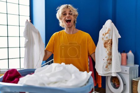 Photo for Young man holding clean white t shirt and t shirt with dirty stain celebrating crazy and amazed for success with open eyes screaming excited. - Royalty Free Image