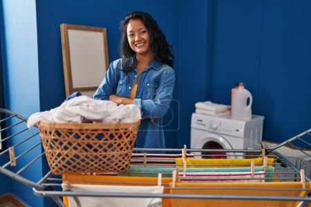 Foto de Joven mujer asiática colgando ropa en el tendedero cara feliz sonriendo con los brazos cruzados mirando a la cámara. persona positiva. - Imagen libre de derechos