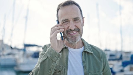 Téléchargez les photos : Moyen Age homme souriant confiant parler sur le smartphone au port - en image libre de droit