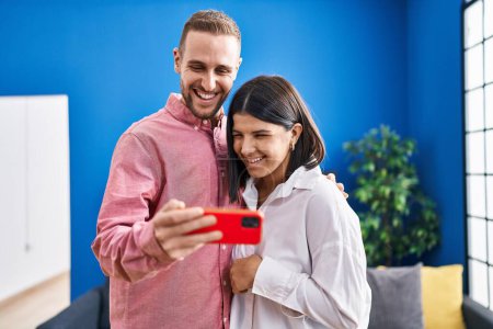 Téléchargez les photos : Homme et femme couple souriant confiant en utilisant smartphone à la maison - en image libre de droit