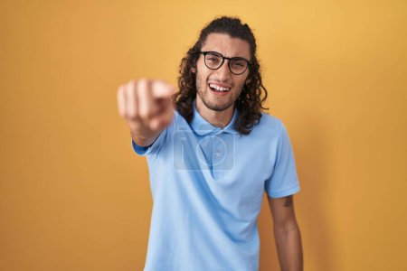 Photo for Young hispanic man standing over yellow background pointing displeased and frustrated to the camera, angry and furious with you - Royalty Free Image
