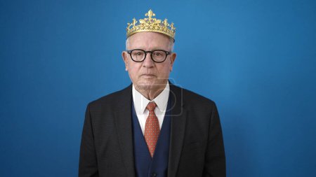 Téléchargez les photos : Senior homme d'affaires portant la couronne sur fond bleu isolé - en image libre de droit
