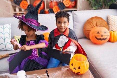 Téléchargez les photos : Adorable afro-américain garçon et fille ayant Halloween partie coupe papier à la maison - en image libre de droit