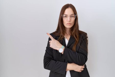 Photo for Beautiful brunette woman wearing business jacket and glasses pointing with hand finger to the side showing advertisement, serious and calm face - Royalty Free Image