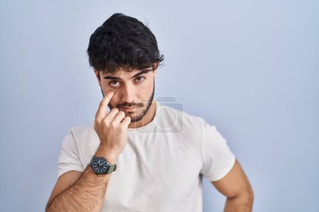 Photo for Hispanic man with beard standing over white background pointing to the eye watching you gesture, suspicious expression - Royalty Free Image