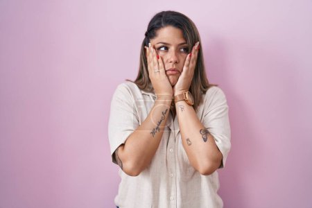 Foto de Mujer rubia de pie sobre fondo rosa manos cansadas cubriendo la cara, depresión y tristeza, molesto e irritado por el problema - Imagen libre de derechos