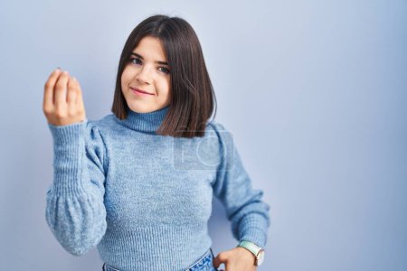 Téléchargez les photos : Young hispanic woman standing over blue background doing italian gesture with hand and fingers confident expression - en image libre de droit