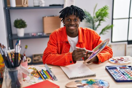 Téléchargez les photos : Africain américain artiste souriant dessin confiant sur ordinateur portable au studio d'art - en image libre de droit