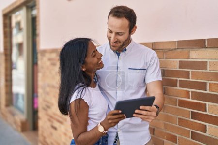 Foto de Man and woman interracial couple standing together using touchpad at street - Imagen libre de derechos