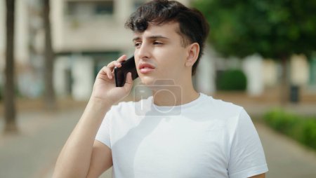 Téléchargez les photos : Non binary man talking on smartphone with worried expression at park - en image libre de droit