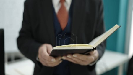 Photo for Senior standing reading book at university classroom - Royalty Free Image