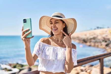 Téléchargez les photos : Jeune femme brésilienne prenant une photo selfie avec smartphone en plein air souriant heureux pointant avec la main et le doigt - en image libre de droit