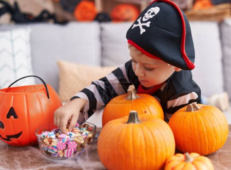 Photo for Adorable caucasian boy wearing pirate costume holding sweet at home - Royalty Free Image