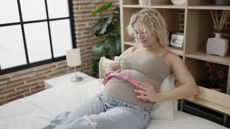 Téléchargez les photos : Jeune femme enceinte souriant confiant mettre des écouteurs sur le ventre à la chambre - en image libre de droit