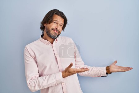 Foto de Guapo hombre de mediana edad con elegante camisa de fondo invitando a entrar sonriente natural con la mano abierta - Imagen libre de derechos