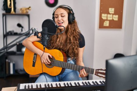 Photo for Young beautiful hispanic woman musician singng song playing classical guitar at music studio - Royalty Free Image