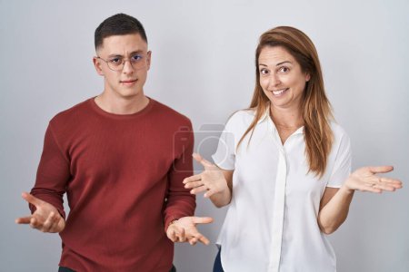 Photo for Mother and son standing together over isolated background clueless and confused with open arms, no idea concept. - Royalty Free Image